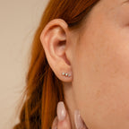 A close-up shows a person with long red hair wearing three Opal Diamond Bar Studs, gently touching their neck.