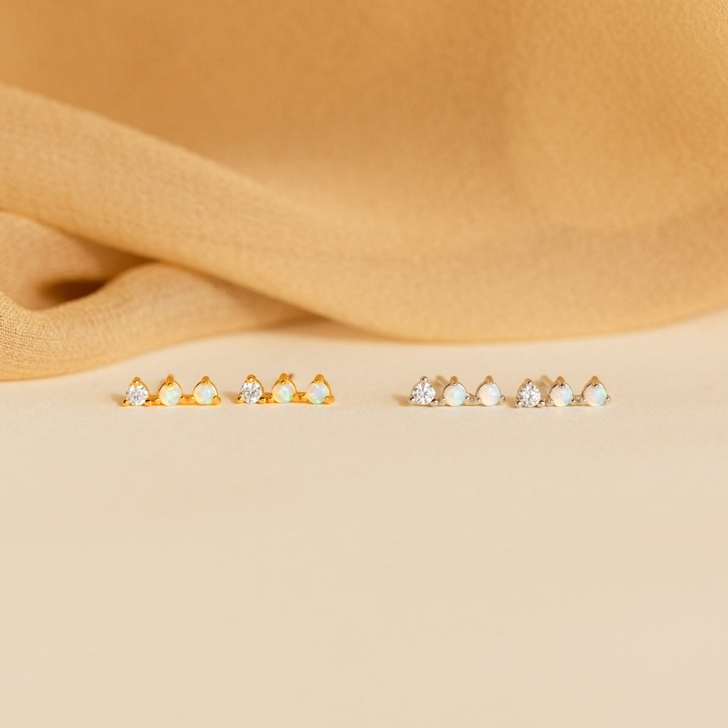 A row of opal earrings with small stones, featuring sparkling Opal Diamond Bar Studs.