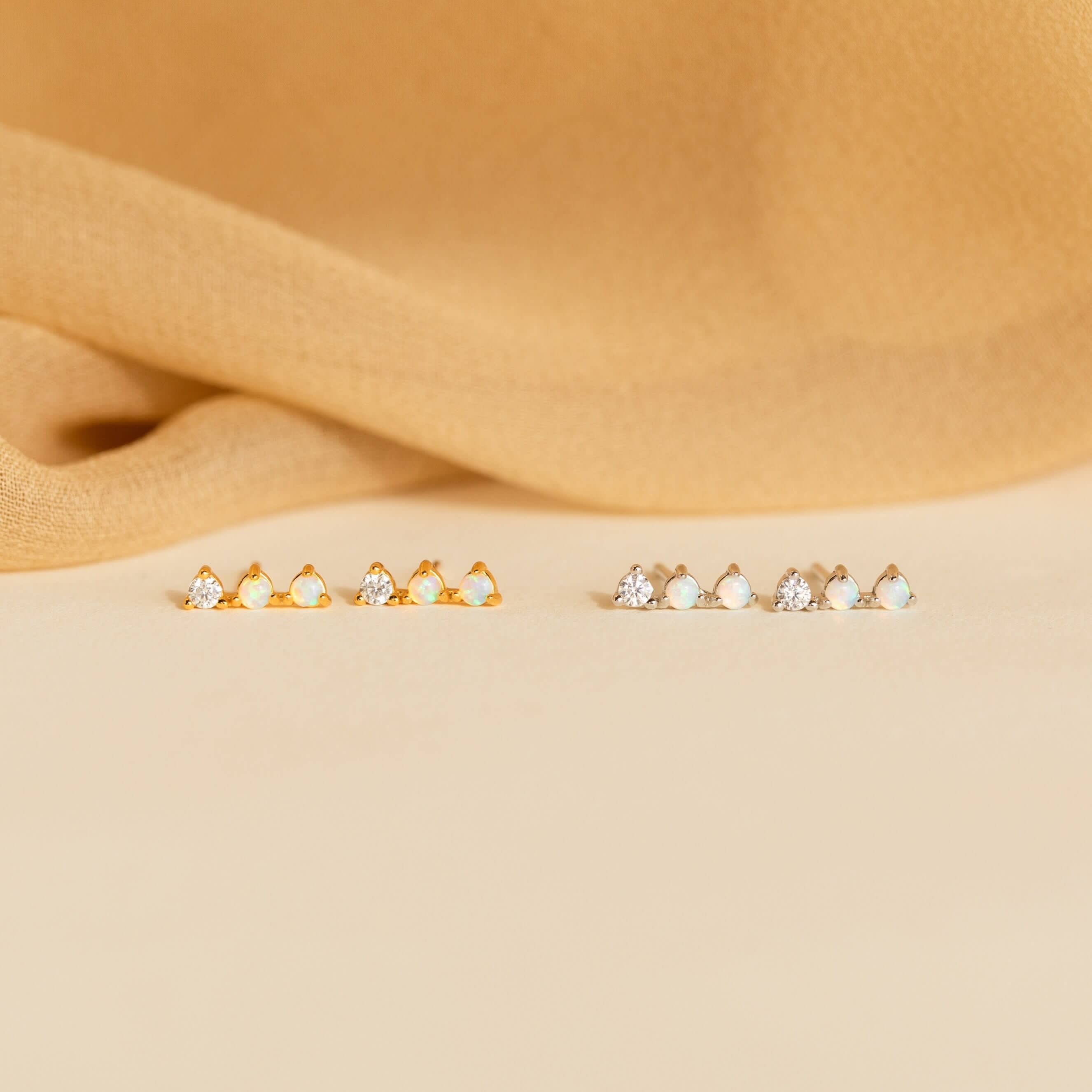 A row of opal earrings with small stones, featuring sparkling Opal Diamond Bar Studs.