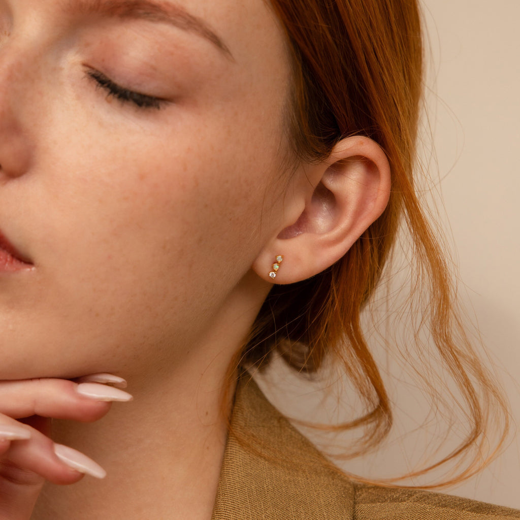 A close-up of a woman's face highlights her radiant beauty, enhanced by the elegant Opal Diamond Bar Studs.