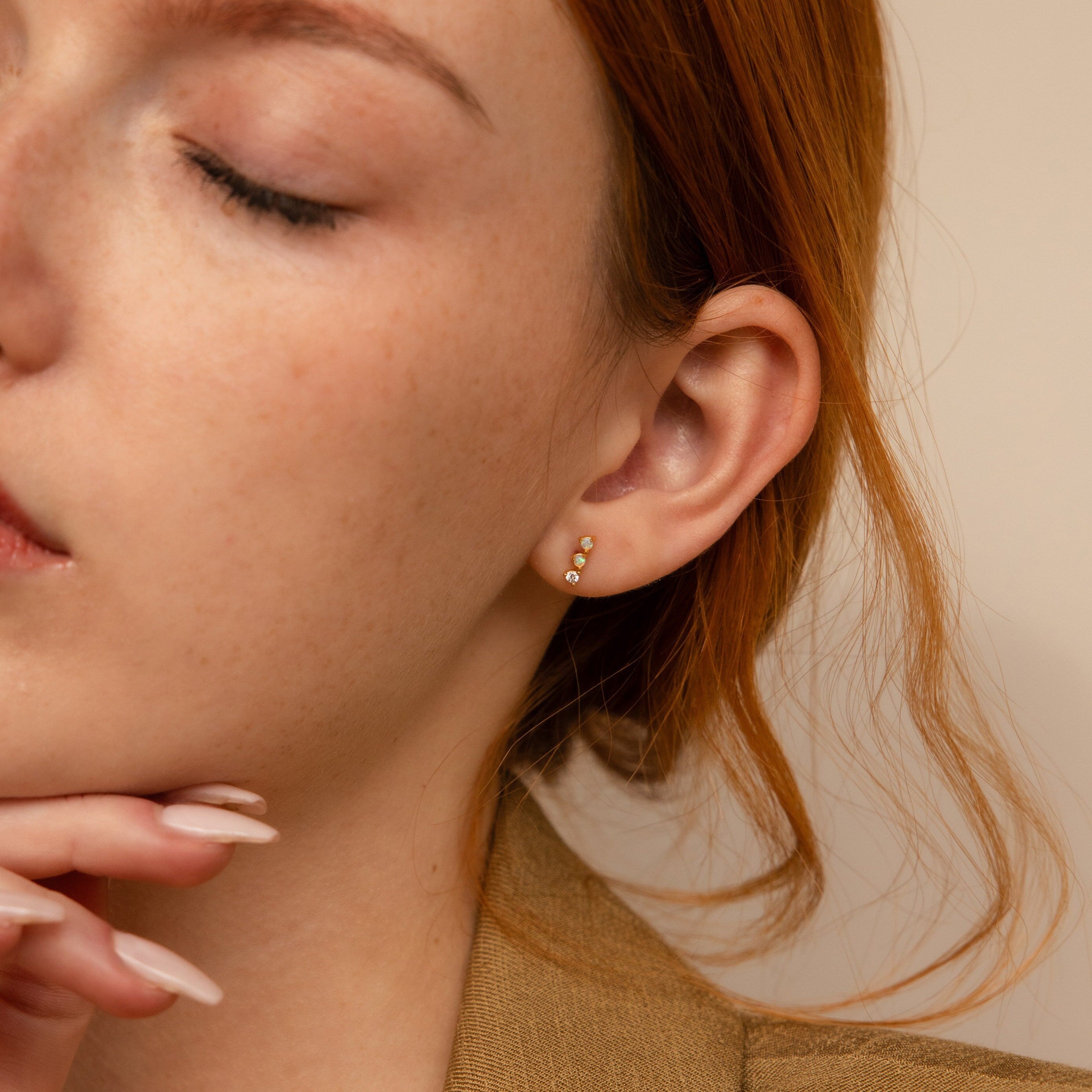 A close-up of a woman's face highlights her radiant beauty, enhanced by the elegant Opal Diamond Bar Studs.
