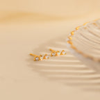 The Opal Diamond Bar Studs, featuring delicate gold settings with sparkling opals and diamonds, rest beside a decorative scalloped-edge dish.