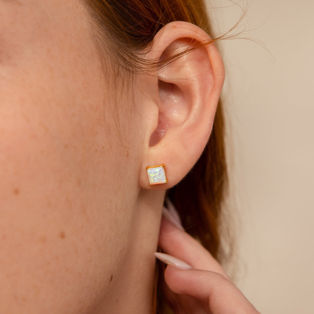 Close-up of a woman's ear wearing Princess Cut Opal Studs—vintage-inspired earrings with a gold setting that add timeless elegance.