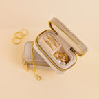 The Mini Travel Jewelry Box in beige velvet with a gold zipper is perfect for organizing rings and earrings while traveling; keep your bracelets nearby.