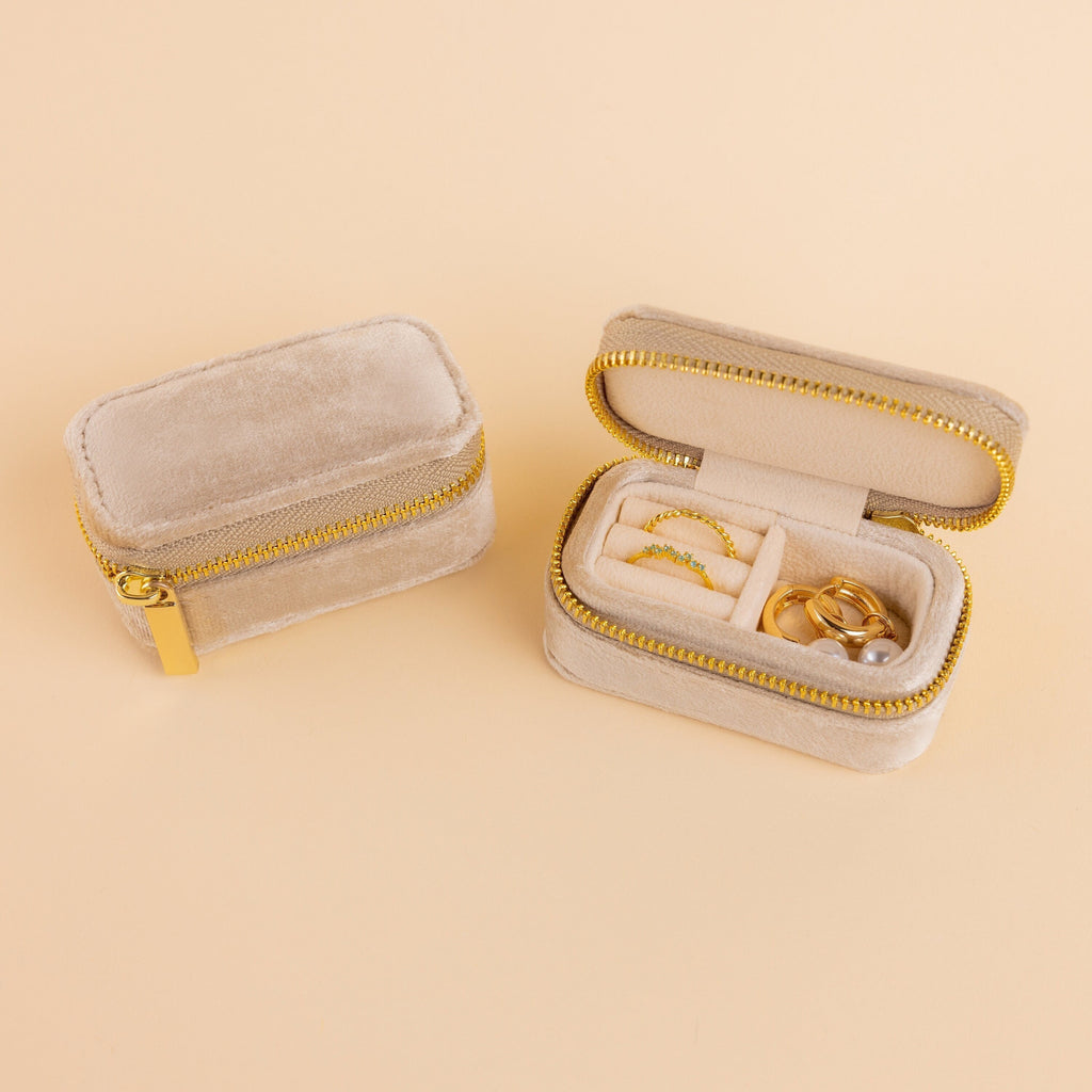 Two small beige Mini Travel Jewelry Boxes in velvet, each with a gold zipper; one is open to display rings and earrings inside—an elegant organizer perfect for travel.