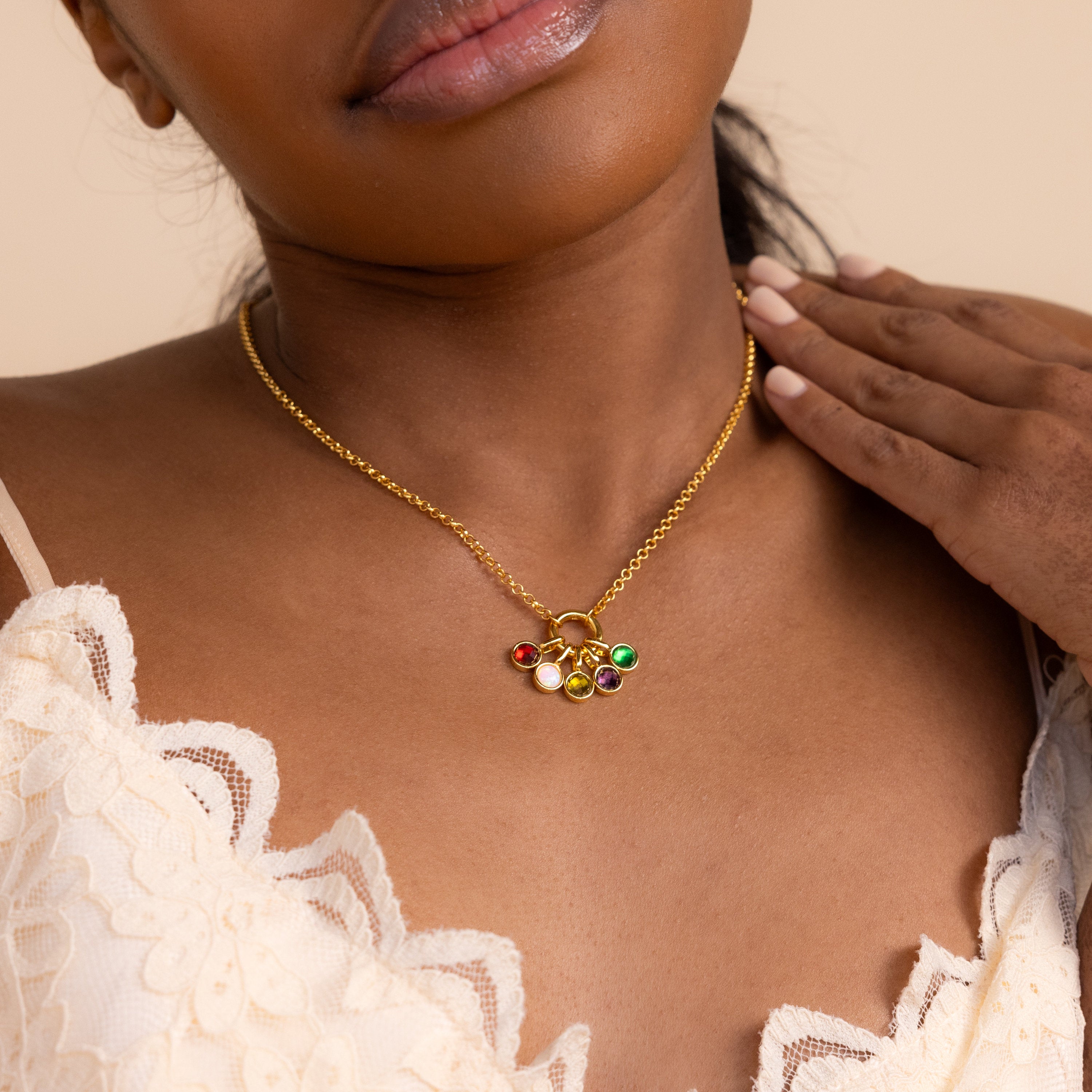 Model wears gold rolo circle necklace with five signet birthstone charms dangling from it