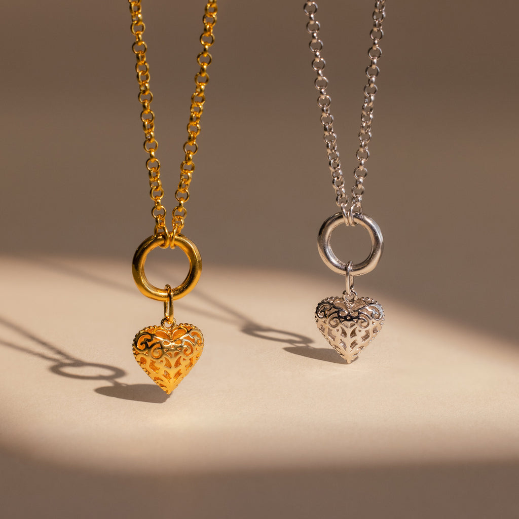 Two heart-shaped pendant necklaces, one gold and one silver, displayed side by side on a neutral background—perfect for adding the Vintage Heart Charm in Sterling Silver to your jewelry collection.