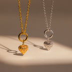 Two heart-shaped pendant necklaces, one gold and one silver, displayed side by side on a neutral background—perfect for adding the Vintage Heart Charm in Sterling Silver to your jewelry collection.