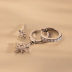 The Opal Starburst Earrings Set, featuring three silver earrings with star and gemstone details, is displayed on a beige background for a dazzling effect.