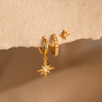 The Opal Starburst Earrings Set showcases three gold earrings with star and pearl-like details, elegantly displayed on textured beige paper—a stunning addition to your jewelry collection.