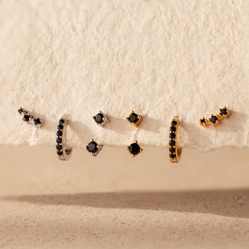 The Black Diamond Earrings Set features bold huggie hoops and climber studs, each adorned with striking black stones for a captivating look.