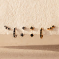 The Black Diamond Earrings Set features bold huggie hoops and climber studs, each adorned with striking black stones for a captivating look.