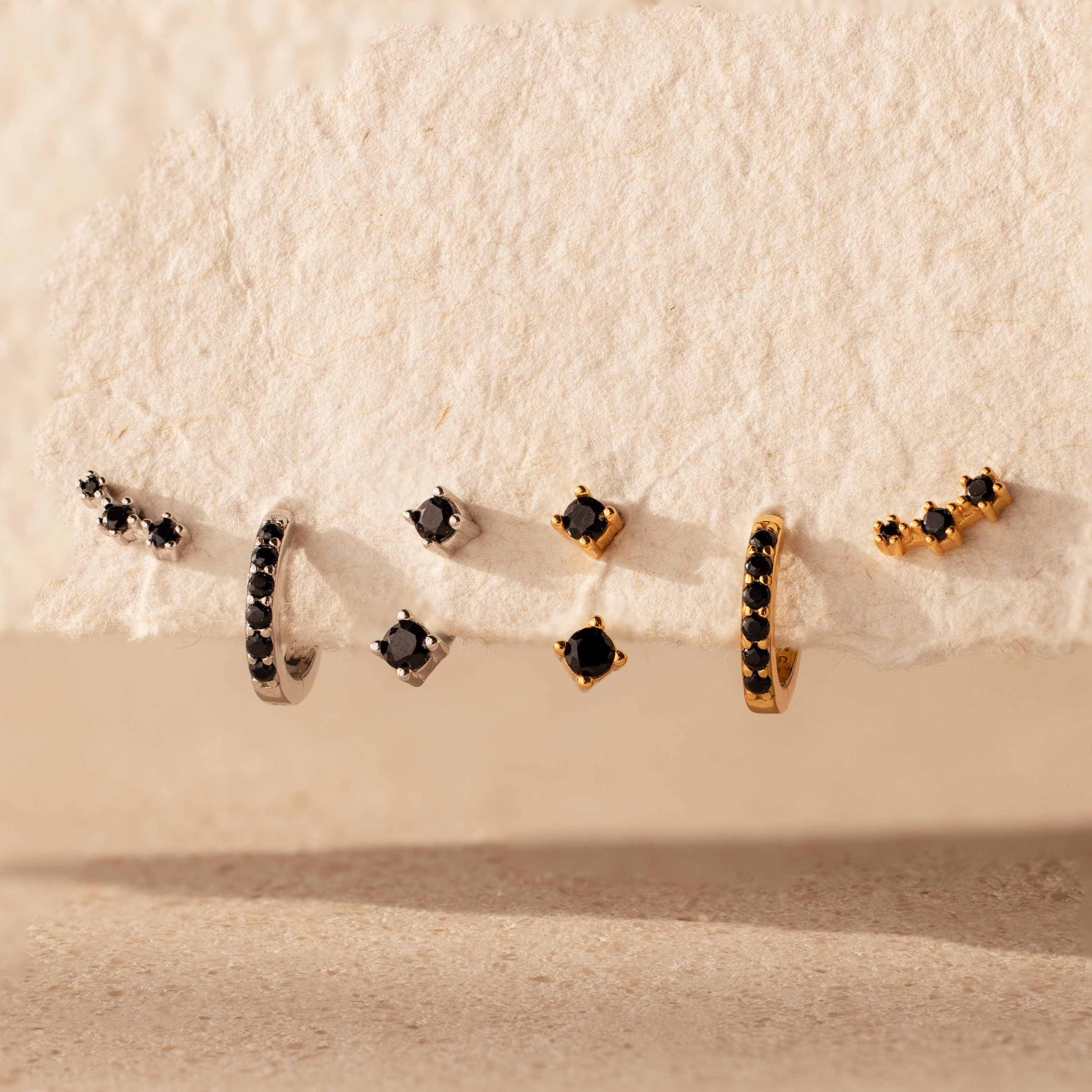 The Black Diamond Earrings Set features bold huggie hoops and climber studs, each adorned with striking black stones for a captivating look.