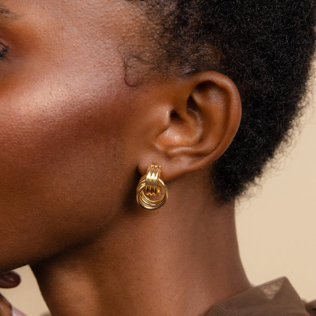Close-up of a person wearing the Triple Knot Earrings—gold hoops with a textured knot design, making them an elegant anniversary gift.