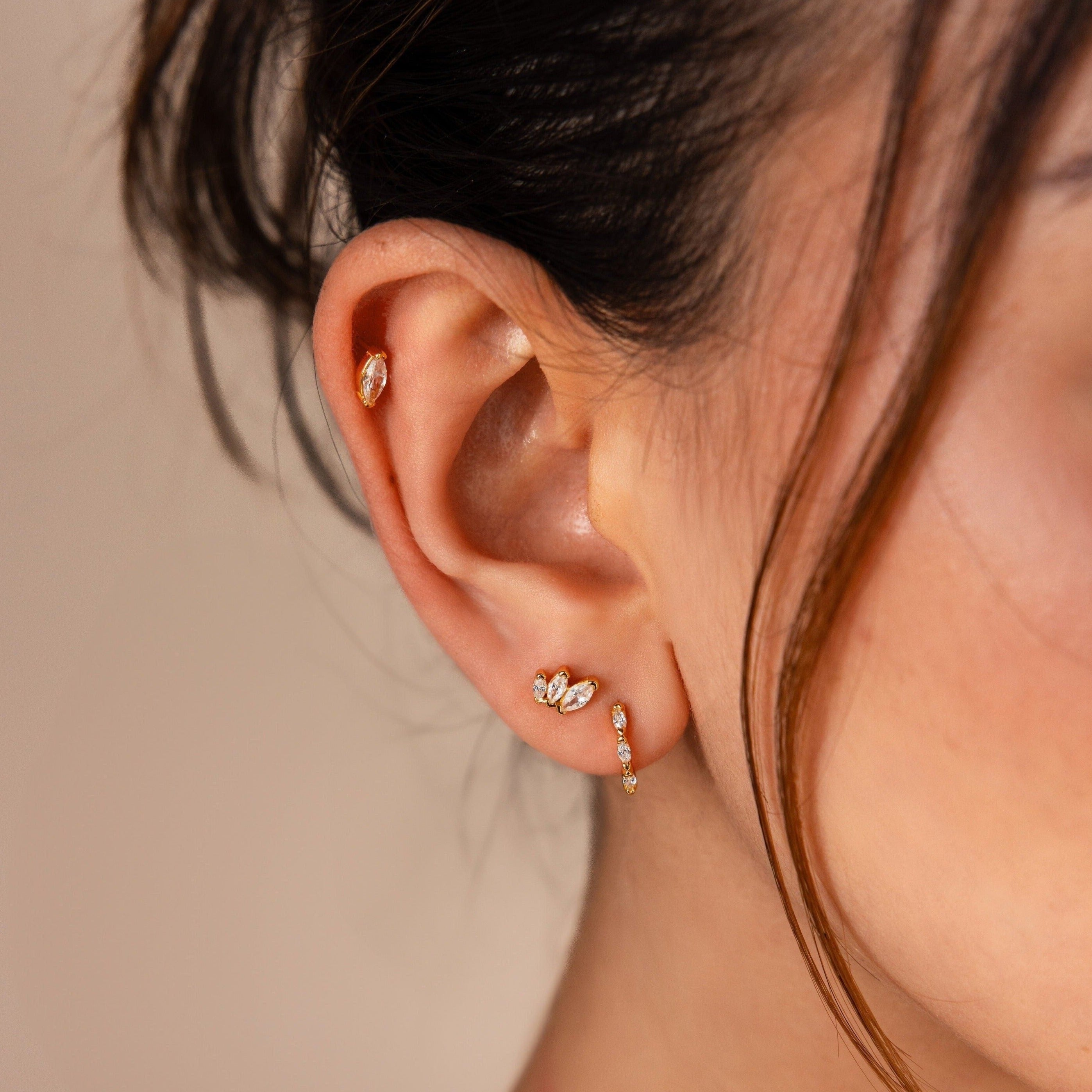 A close-up of a woman's ear adorned with the Marquise Diamond Earrings Set and gold studs, capturing wedding elegance—an inspiring choice for bridesmaid gifts.