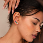 A woman with nude nails wears the Flower Flat Back Studs Set—three colorful flower earrings—in a close-up side profile. These comfortable, stylish flat back studs are perfect for everyday wear.