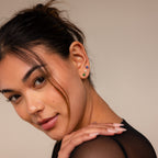 Woman with dark hair wearing the Flower Flat Back Studs Set and a black sheer top, looking over her shoulder and smiling.