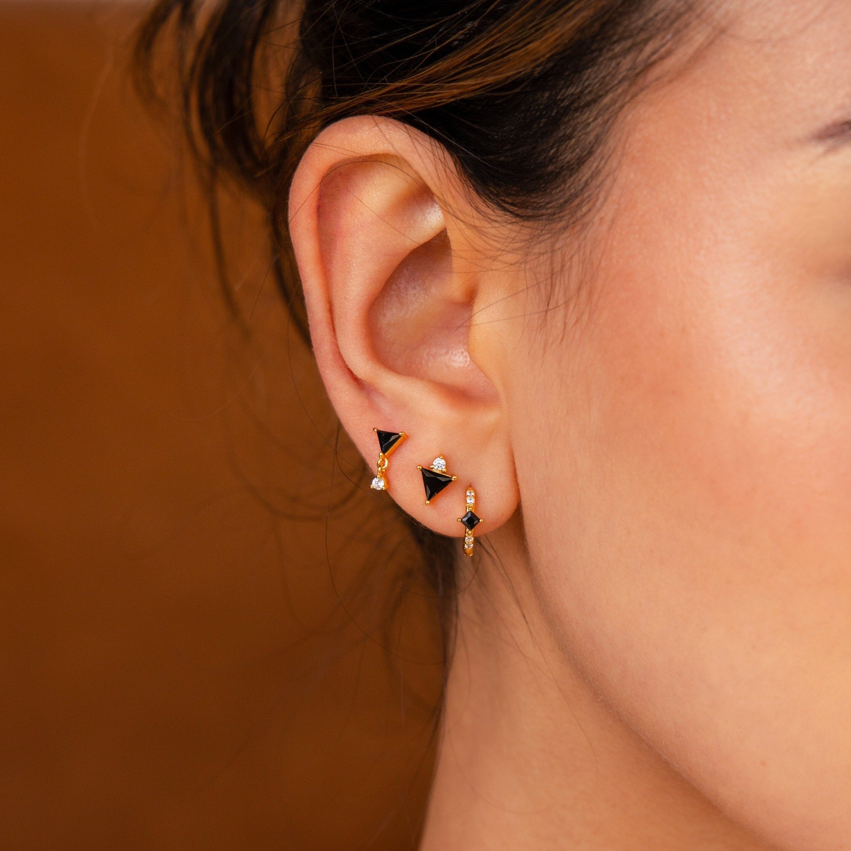 Close-up of a woman’s ear wearing the Black Art Deco Earrings Set—gold geometric earrings with black triangle and round gemstone details, capturing minimalist style and Black Art Deco elegance.