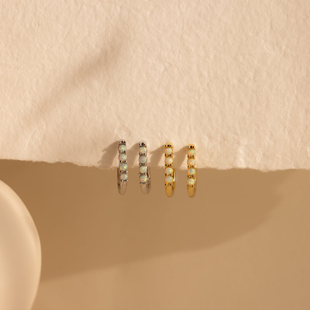 Two pairs of Opal Link Hoops—one silver pair with gemstone accents and one gold pair—are showcased on textured beige paper.