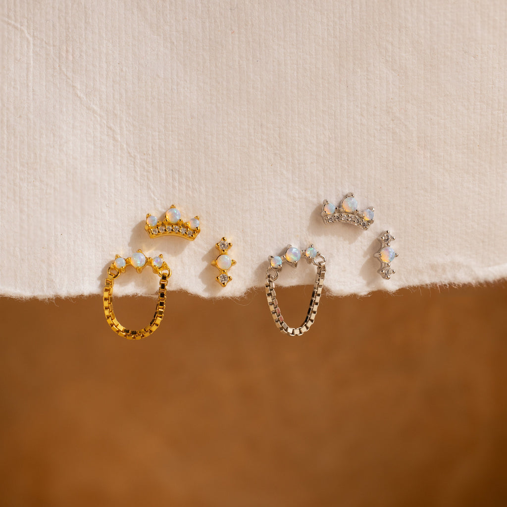 The Opal Cartilage Studs Set is displayed elegantly on a white cloth alongside Pavé Diamond earrings.