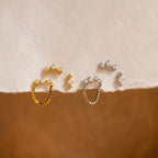 The Opal Cartilage Studs Set is displayed elegantly on a white cloth alongside Pavé Diamond earrings.