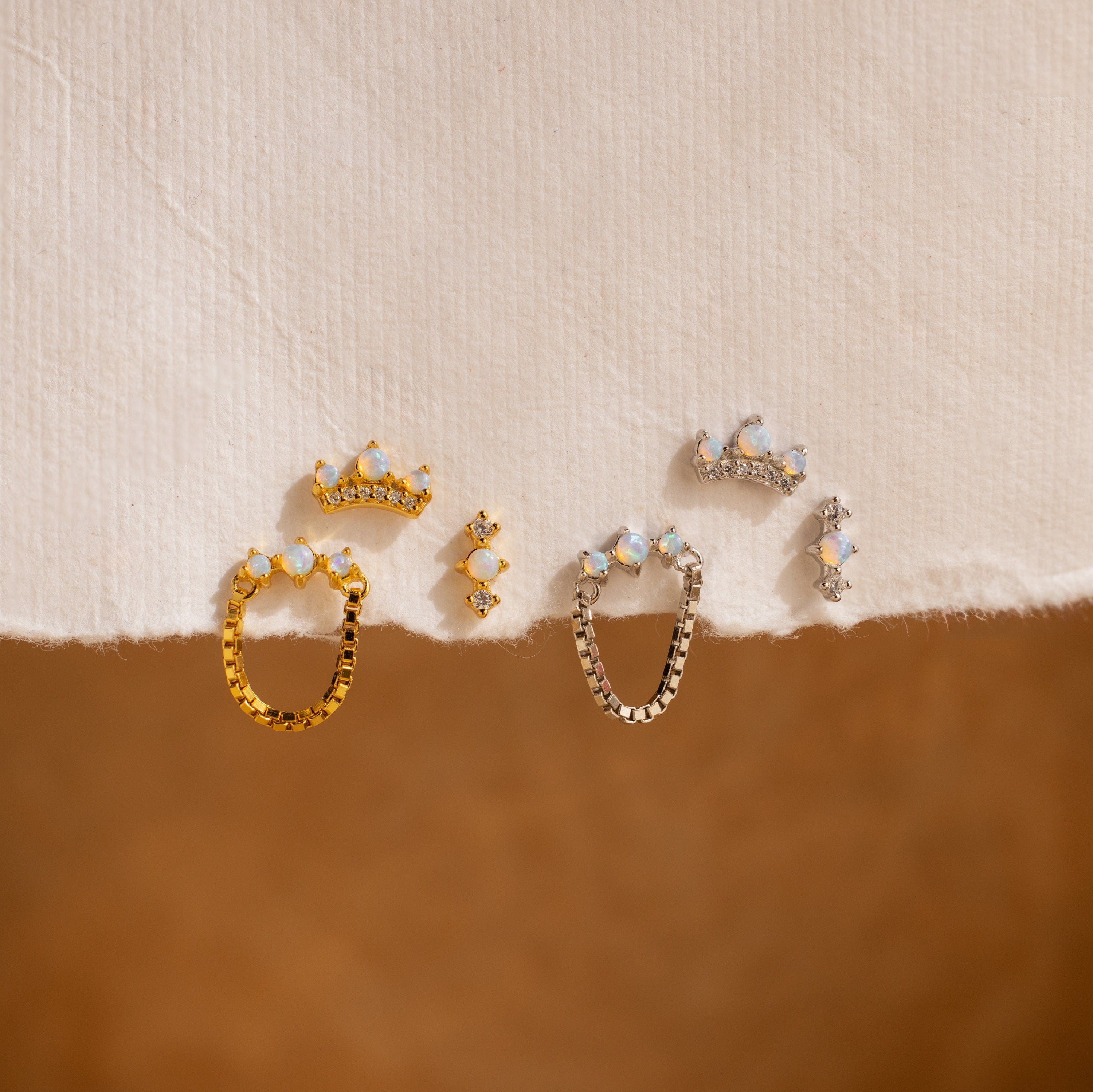 The Opal Cartilage Studs Set is displayed elegantly on a white cloth alongside Pavé Diamond earrings.