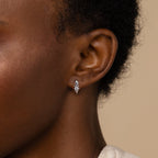 Close-up of a woman's ear wearing Opal and Diamond Huggies, small silver hoop earrings accented with a round gemstone, showcasing the refined elegance of minimalist jewelry.