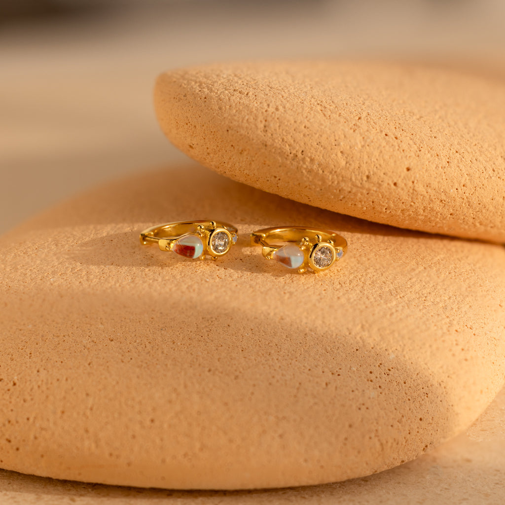 Opal and Diamond Huggies displayed on smooth, beige textured stones.