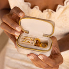 A woman holds an open Mini Travel Jewelry Box featuring gold rings and a beaded ring inside.