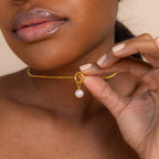 Woman holding the Classic Pearl Charm in Sterling Silver close to her neck, highlighting her glossy lips and nude nails.