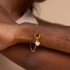 The Mother of Pearl Heart Charm in 18K Gold rests on a wrist with vitiligo, blending elegance and vintage charm.