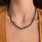 A woman in a mustard top showcases the allure of the Tanzanite Beaded Necklace, featuring gold accents and mystical charm.