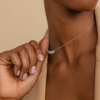 Close-up of a person holding the Pave Link Necklace, featuring interlocking links and a small knot pendant, offering an elegant touch to any jewelry collection.