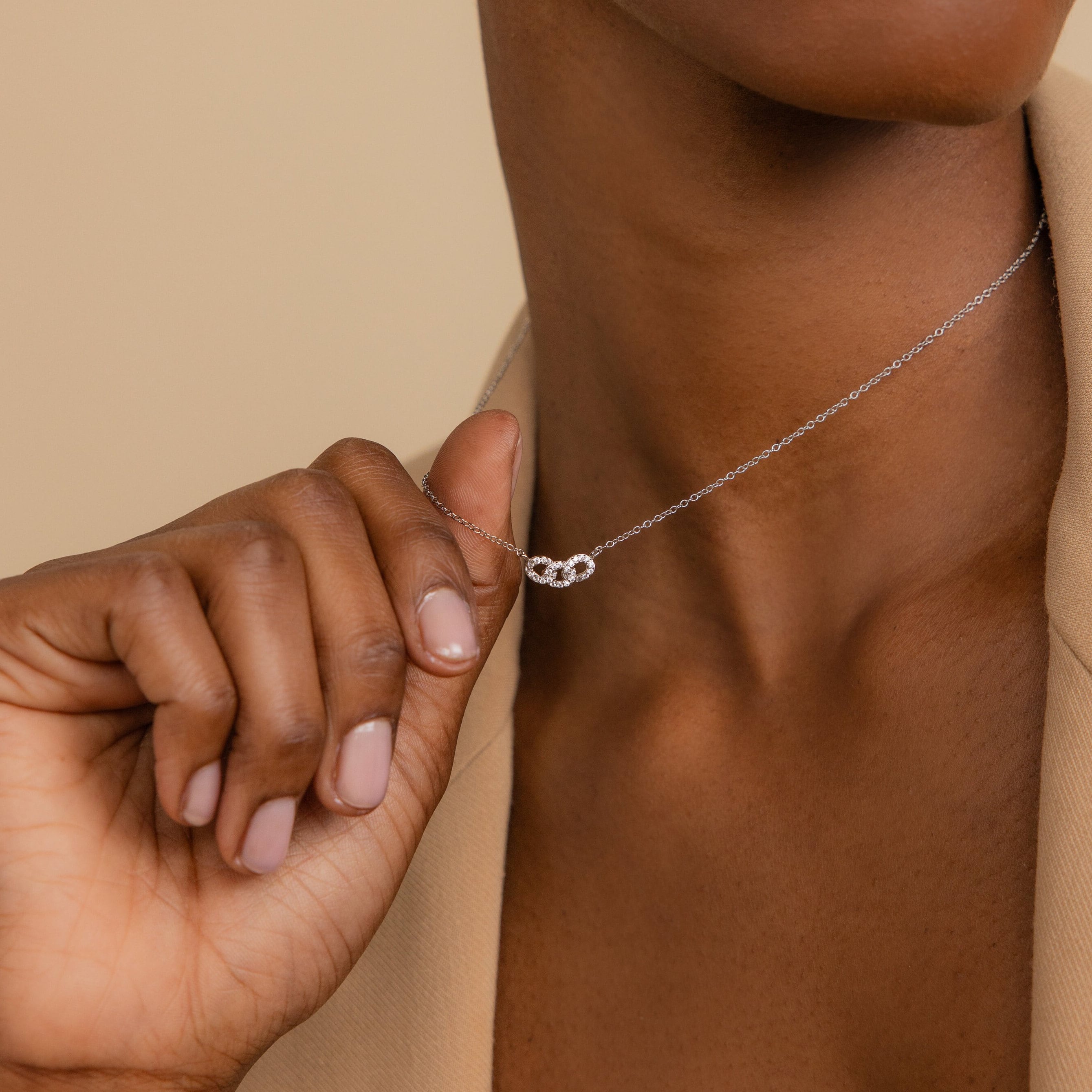 Close-up of a person holding the Pave Link Necklace, featuring interlocking links and a small knot pendant, offering an elegant touch to any jewelry collection.