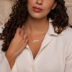 A woman in a cream ribbed shirt models the Pave Handwriting Necklace, personalized with "Jessica" in gold—an ideal choice for statement jewelry lovers.