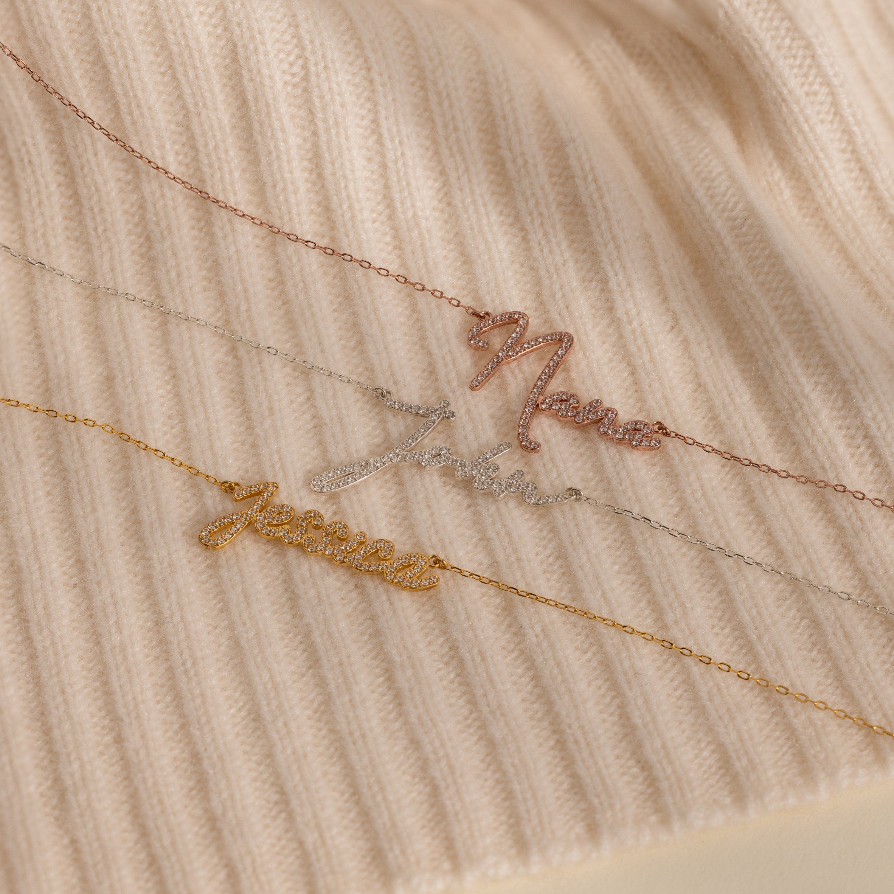The Pave Handwriting Necklace is shown spelling "Name," "Intan," and "Jesica" on ribbed beige fabric—a chic statement accessory for any occasion.