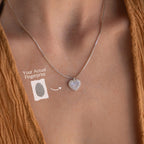 The Pave Fingerprint Heart Necklace, featuring an engraved fingerprint heart pendant, rests on a person's neck and is displayed with a sample fingerprint image and label.