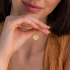 A woman wearing a brown top holds a personalized Pave Fingerprint Heart Necklace close to her face.