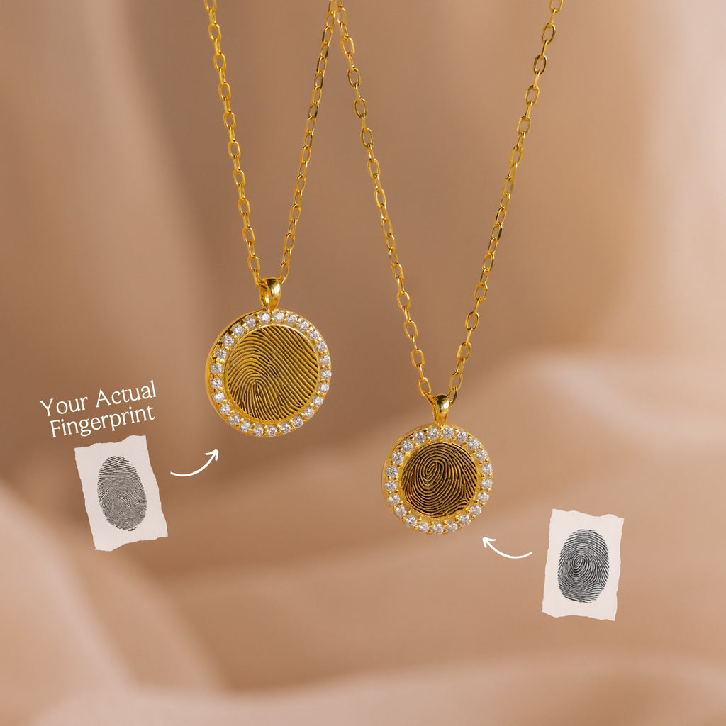 Two Pave Fingerprint Coin Necklaces with custom engraved fingerprint designs are displayed beside matching fingerprint images on a soft beige background—a meaningful memorial gift.