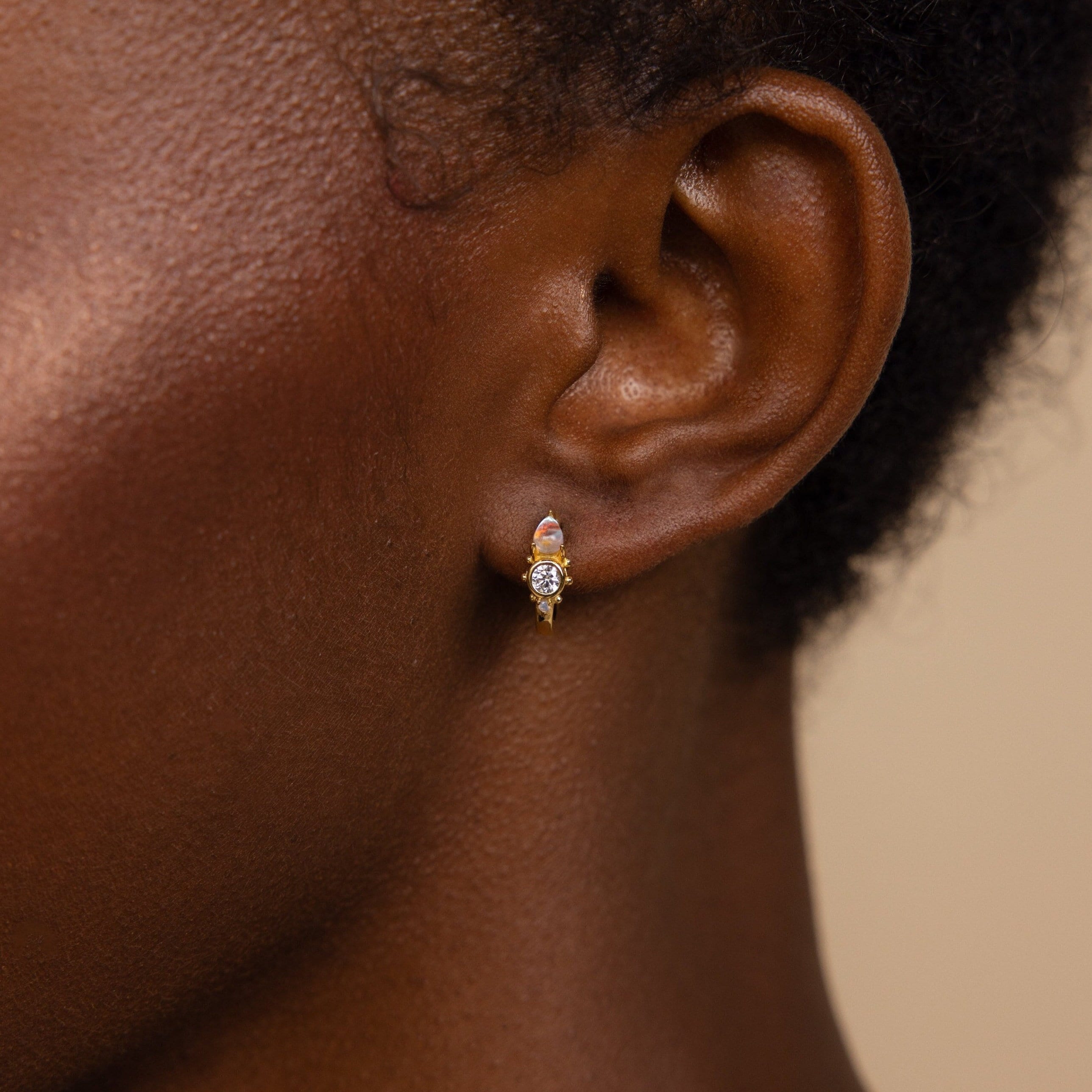 A close-up of a woman's ear adorned with Opal and Diamond Huggies.