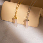 Crystal Quartz Necklaces—two hexagonal point pendants, one on a gold chain and one on silver, beautifully displayed on a beige stand—add positive energy and elegance to your style.