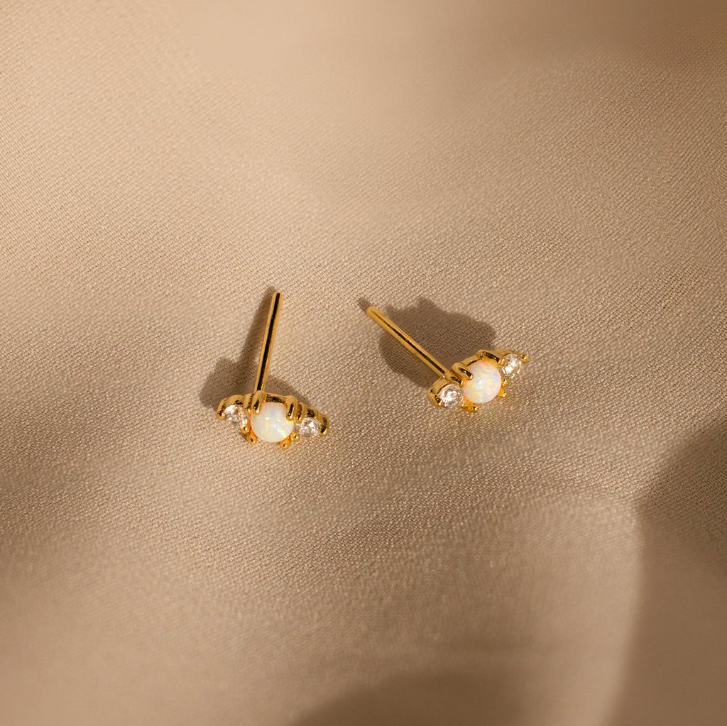 Opal and Diamond Studs, ideal for cartilage or helix piercings, are displayed on light beige satin fabric.