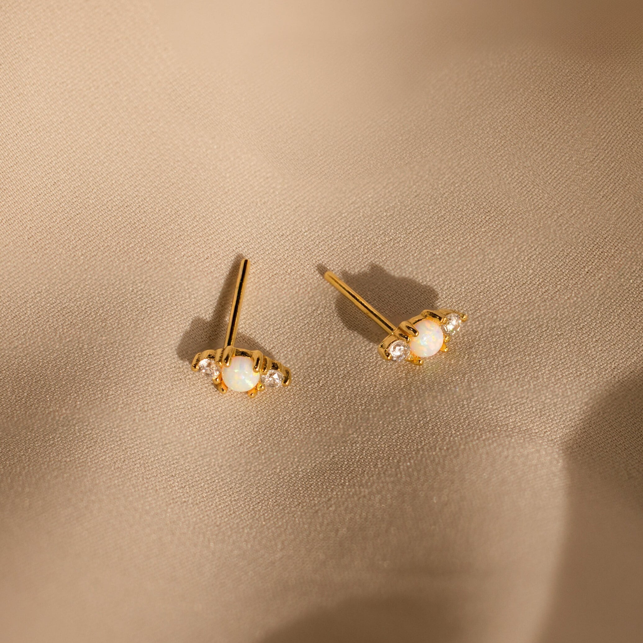 Opal and Diamond Studs, ideal for cartilage or helix piercings, are displayed on light beige satin fabric.