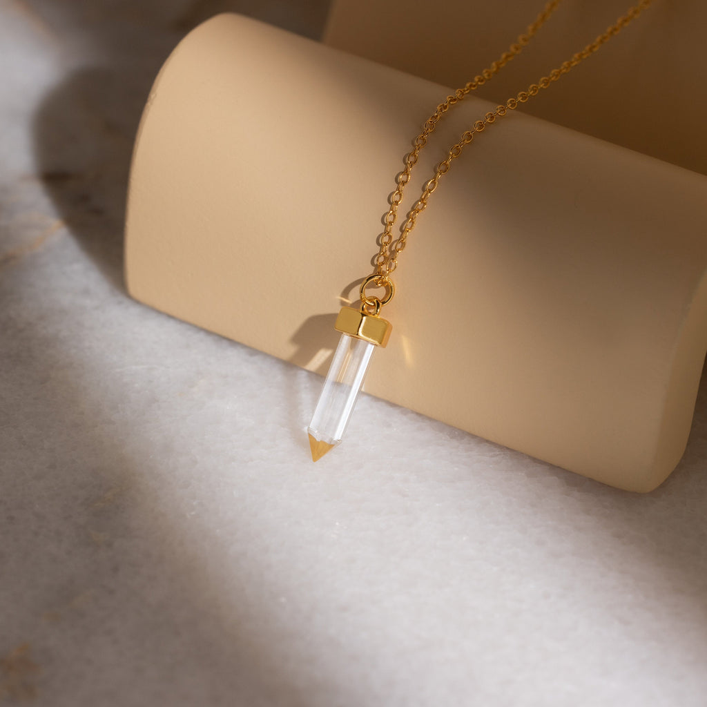 The Clear Quartz Necklace features a hexagonal quartz point pendant on a gold chain, perfect for adding crystal elegance to any jewelry collection.