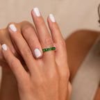 A hand with white-painted nails showcases the Birthstone Inlay Band—a silver ring featuring vibrant green gemstones on the ring finger for a striking statement look.