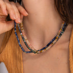 A woman in a brown top holds a double-strand, multicolored Rose Quartz Beaded Necklace against her neck—an elegant gift for your best friend.