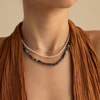 A woman radiates earthy elegance wearing a brown textured sleeveless top and three layered necklaces, including the Moss Agate Beaded Necklace.