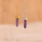Two Amethyst Quartz Necklaces—one on a gold chain and one on a silver chain—are displayed elegantly on a beige background, making them perfect unique gifts.