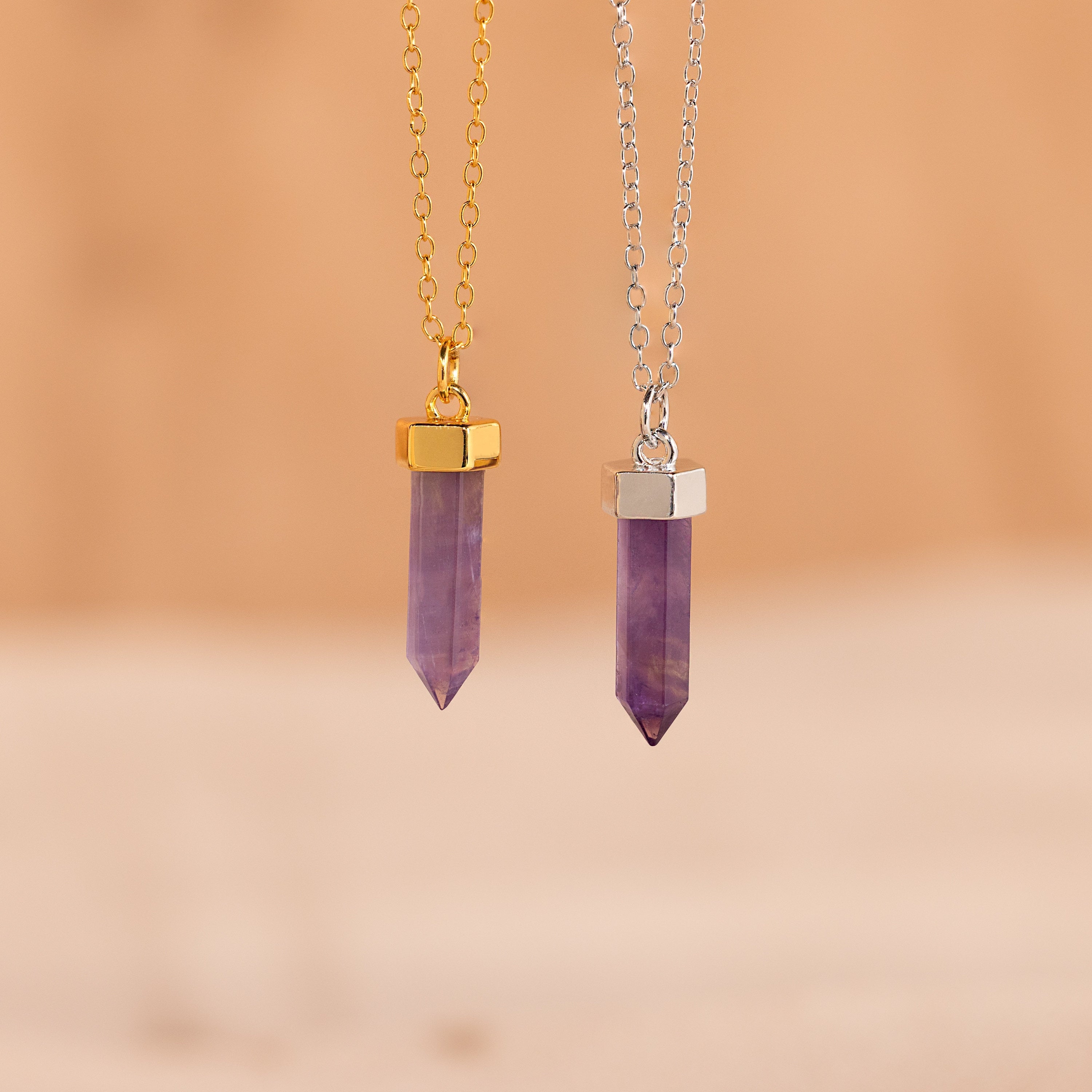 Two Amethyst Quartz Necklaces—one on a gold chain and one on a silver chain—are displayed elegantly on a beige background, making them perfect unique gifts.