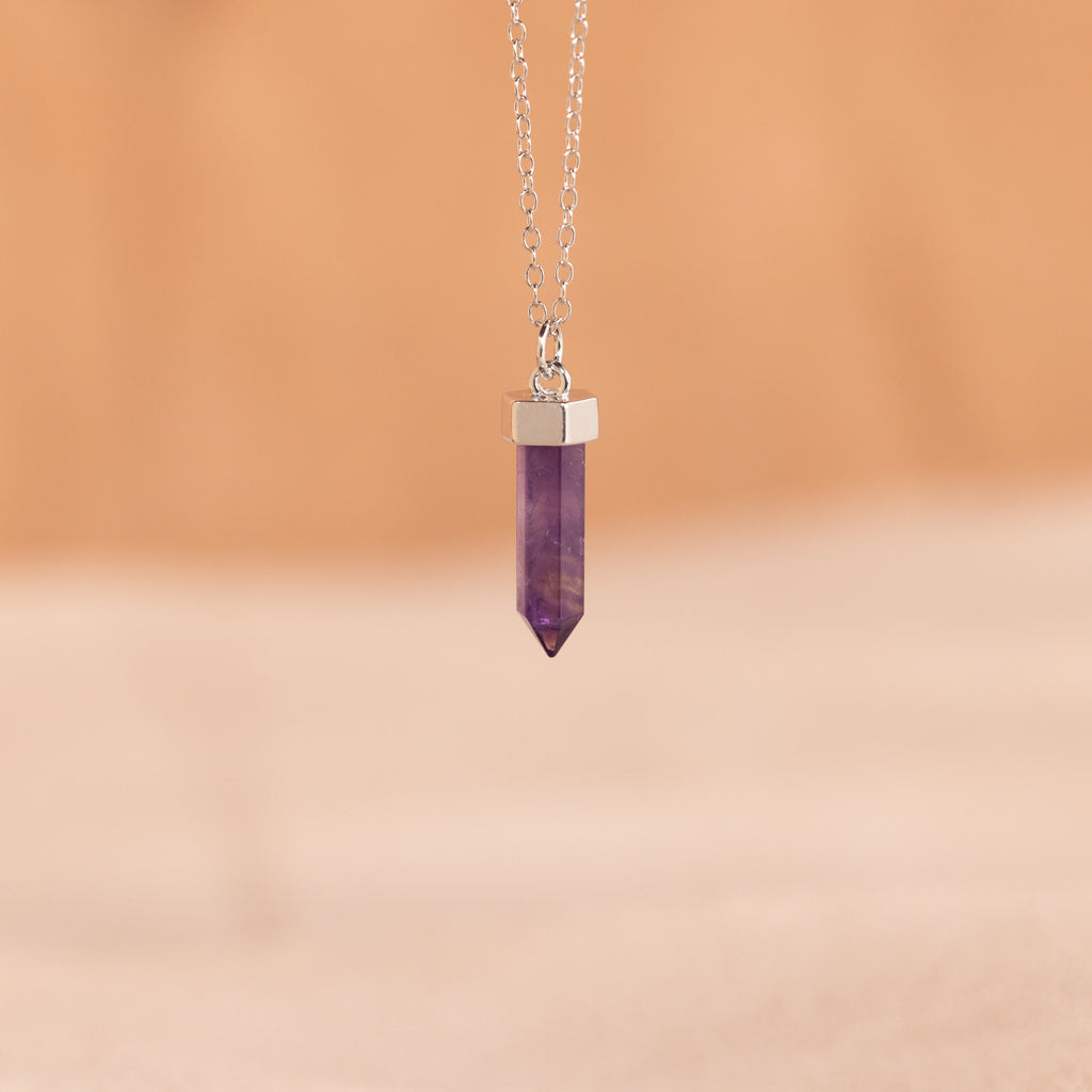 A silver Amethyst Quartz Necklace with a hexagonal pendant displayed on a soft, beige background—a stylish crystal charm and a thoughtful gift idea.